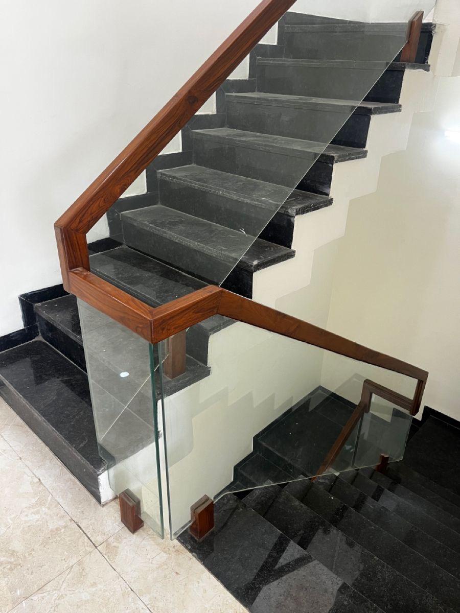 Wood handrail glass railing on dark granite staircase
